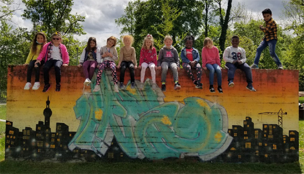 Kindersitzen auf einemn Mauerabschnitt mit Graffitti