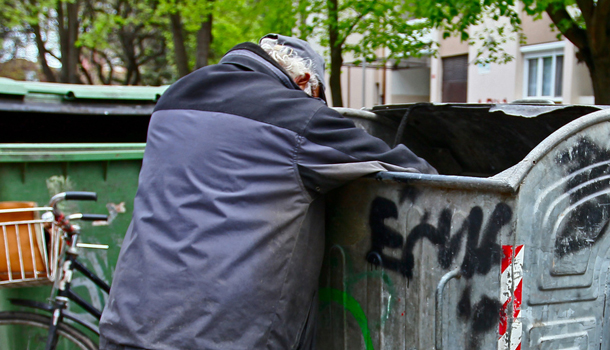 Armut - Das Bild zeigt einen in einer Mülltonne suchenden Mann